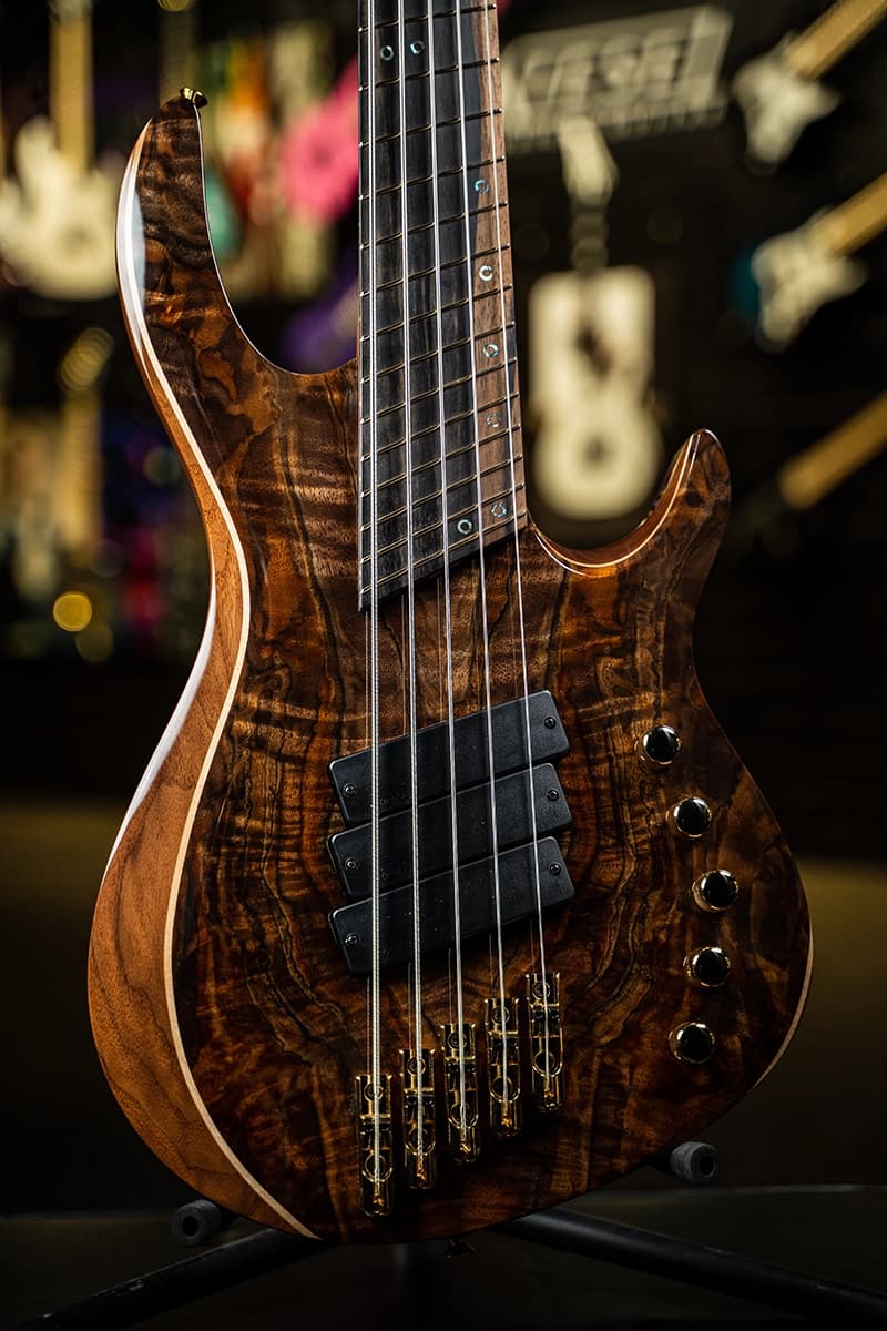 Kiesel Guitars Aries A2 bass with master grade top, maple three piece body binding, alder body, royal ebony fingerboard, dark glass preamp, gold hardware, 5 string multiscale, triple tritium humbuckers, abalone ring staggered offset ring inlays