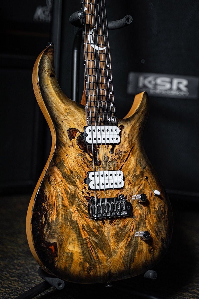 Kiesel Guitars Crescent 7 string tremolo C7X with master grade buckeye top, white pickup coils, chrome hardware, white acrylic crescent moon with staggered offset dot inlays ICSD, royal ebony fingerboard, thin black burst edges, rear of body natural clear, natural body binding