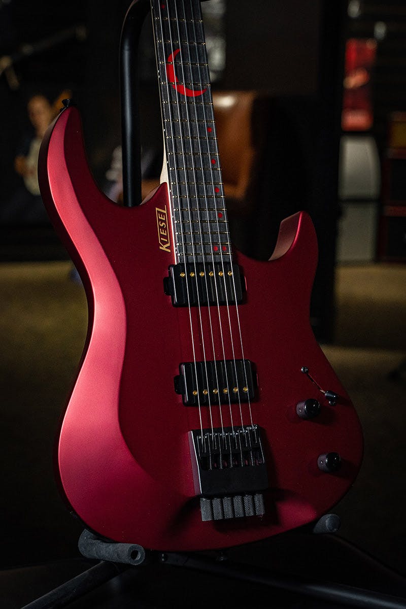 Kiesel Guitars Osiris O6 metallic red finish, clear satin matte top coat, black pickup covers, gold pickup poles, gold logo, red acrylic crescent with staggered offset dot inlays, ebony less coloration fingerboard