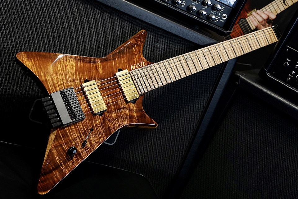 Kiesel Guitars Type-X X6 with koa top, black limba body, gloss top coat, gold pickup covers, gold pole pieces, gold logo, flamed maple fingerboard, white pearl 12th fret K logo with staggered offset dot inlays IKSD