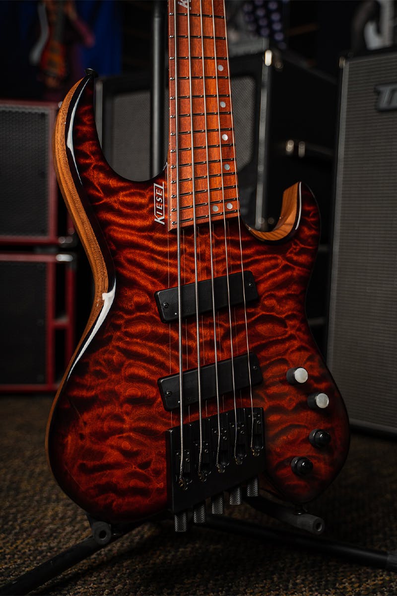/Kiesel Guitars Vader Bass 5 String Multiscale Bass with quilted maple top, black burst edges, translucent red finish, black hardware, white pearl knob inlays, white logo, bloodwood fingerboard, mother of pearl 12th fret logo staggered offset dot inlays, rear of body natural clear RNC, alder body